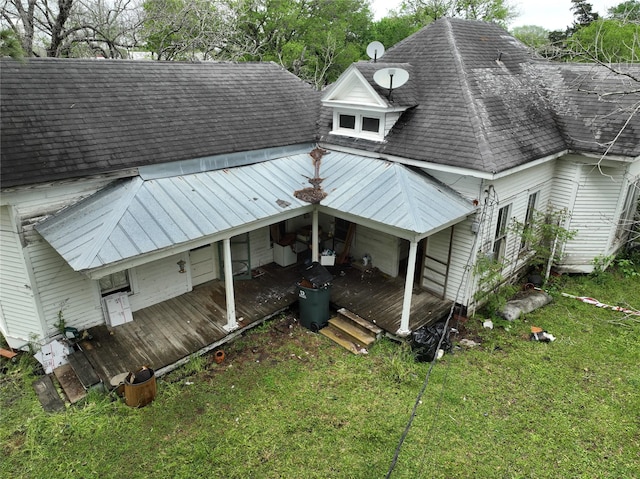back of property with a lawn, roof with shingles, and a porch