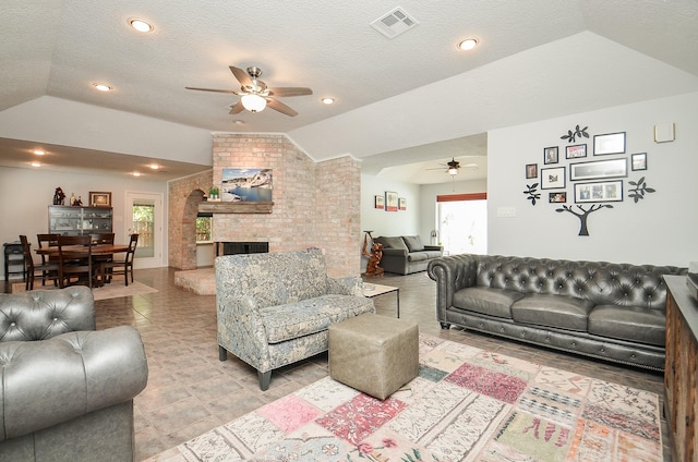 living room featuring ceiling fan, lofted ceiling, a brick fireplace, a textured ceiling, and light tile patterned floors