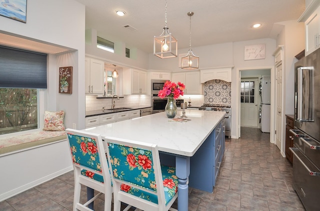 kitchen with white cabinets, tasteful backsplash, high end appliances, a sink, and recessed lighting
