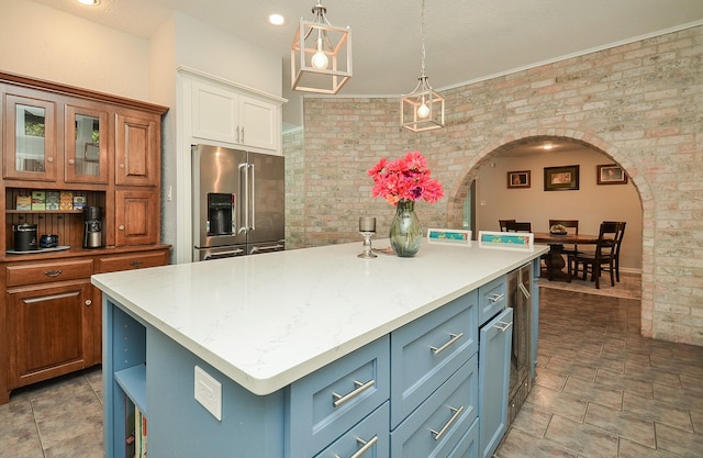 kitchen with high end fridge, arched walkways, brick wall, a kitchen island, and white cabinets