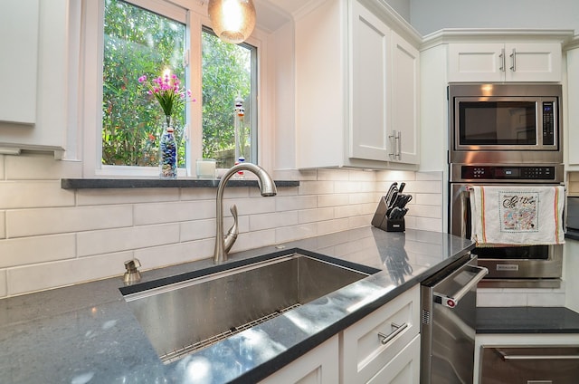 kitchen with a sink, appliances with stainless steel finishes, tasteful backsplash, and white cabinetry