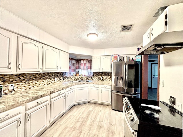 8038 Woodlyn Rd, Houston, TX 77028 - kitchen featuring a textured ceiling, visible vents, light wood-type flooring, white cabinets, and stainless steel appliances