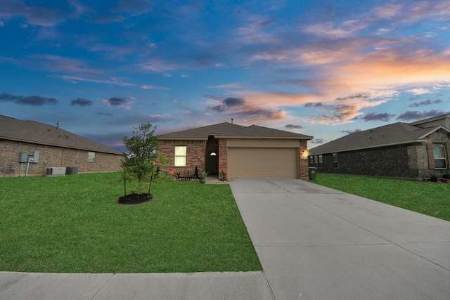 ranch-style home featuring a garage, driveway, cooling unit, brick siding, and a yard