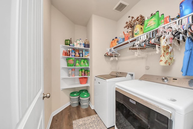 clothes washing area with laundry area, visible vents, wood finished floors, baseboards, and washing machine and clothes dryer