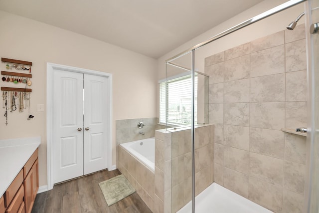 bathroom with vanity, a bath, a stall shower, and wood finished floors