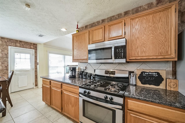20319 Concord Hill Dr, Cypress, TX 77433 - kitchen with a textured ceiling, appliances with stainless steel finishes, decorative backsplash, and dark stone countertops