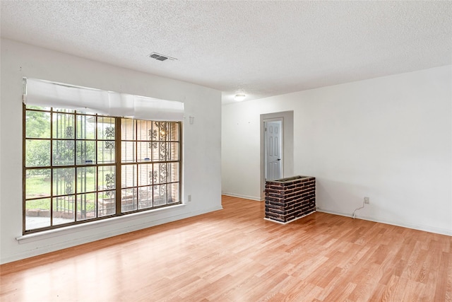 spare room with baseboards, a textured ceiling, visible vents, and wood finished floors