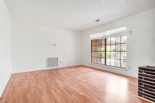 unfurnished living room featuring a textured ceiling, wood finished floors, and visible vents