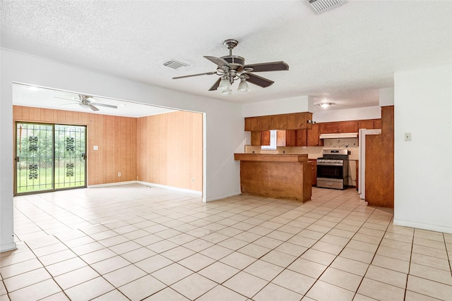 kitchen with stainless steel gas range oven, a peninsula, open floor plan, a ceiling fan, and visible vents