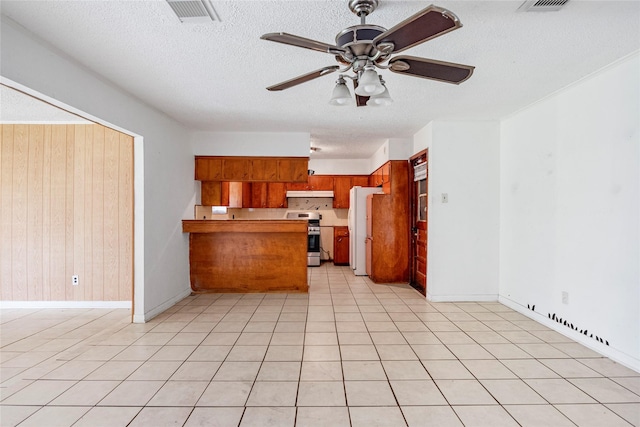 kitchen with visible vents, brown cabinets, freestanding refrigerator, a peninsula, and stainless steel range oven