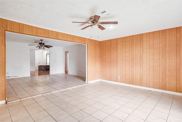 unfurnished room with a ceiling fan, a textured ceiling, and wooden walls