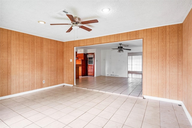 unfurnished room with wooden walls, a textured ceiling, ceiling fan, and visible vents