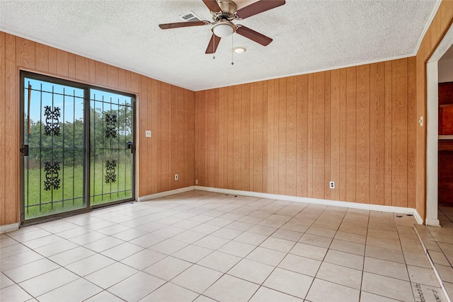 spare room featuring wooden walls, a textured ceiling, a ceiling fan, baseboards, and light tile patterned floors