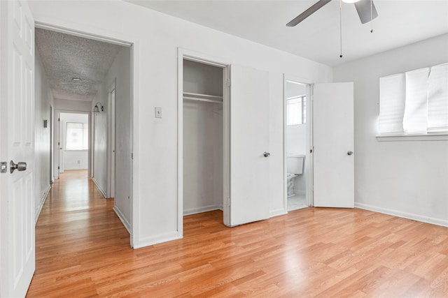 unfurnished bedroom with ceiling fan, baseboards, a closet, light wood-style floors, and ensuite bath