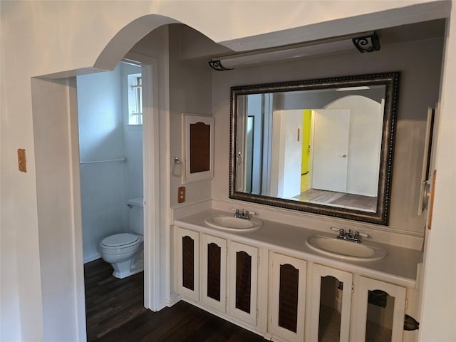 full bath featuring wood finished floors, toilet, and double vanity