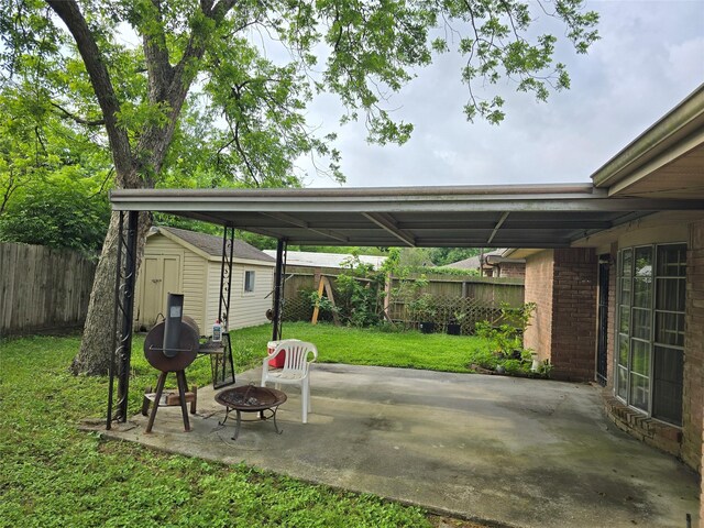 view of car parking with a storage shed, a carport, and an outdoor fire pit