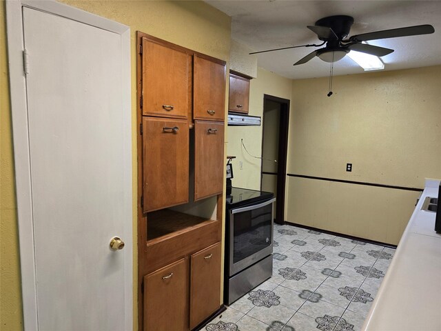 kitchen with electric stove, ceiling fan, brown cabinets, light tile patterned floors, and range hood