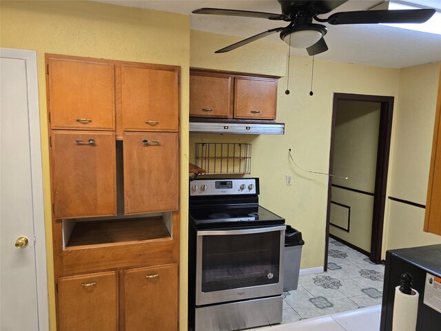 kitchen with electric stove, under cabinet range hood, brown cabinetry, ceiling fan, and light tile patterned floors