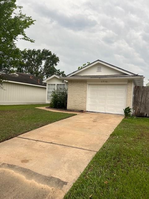 view of front of house featuring a front yard, a garage, brick siding, fence, and concrete driveway