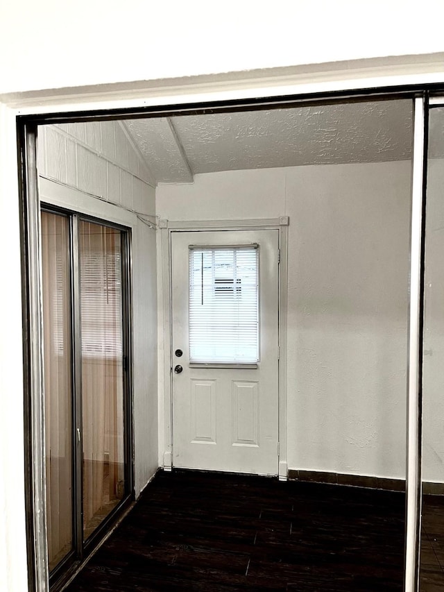 doorway to outside featuring vaulted ceiling and dark wood-type flooring