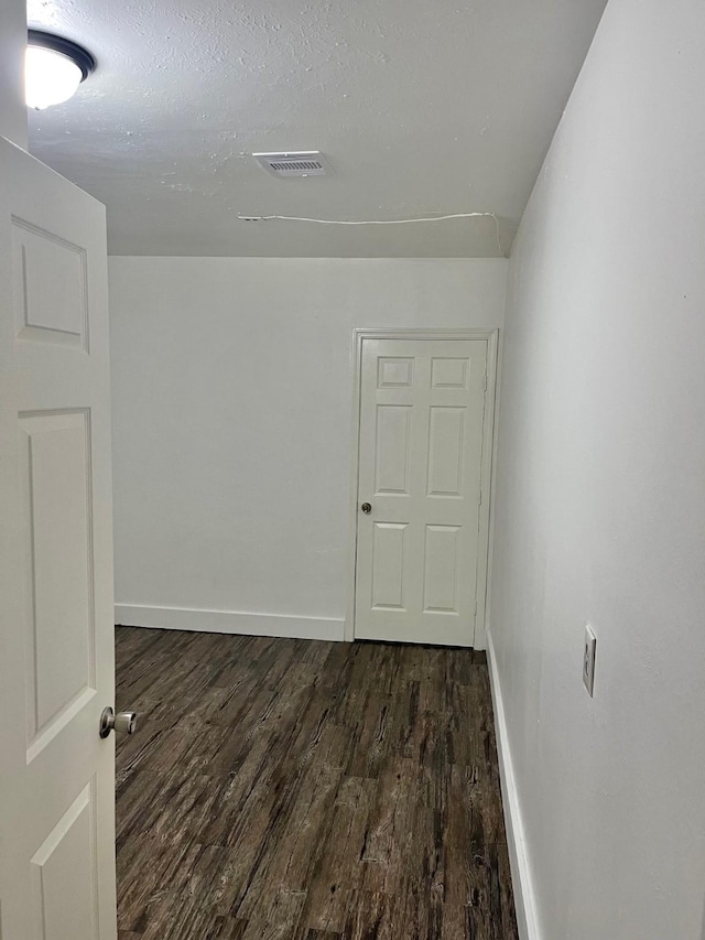 empty room with visible vents, baseboards, and dark wood-style floors