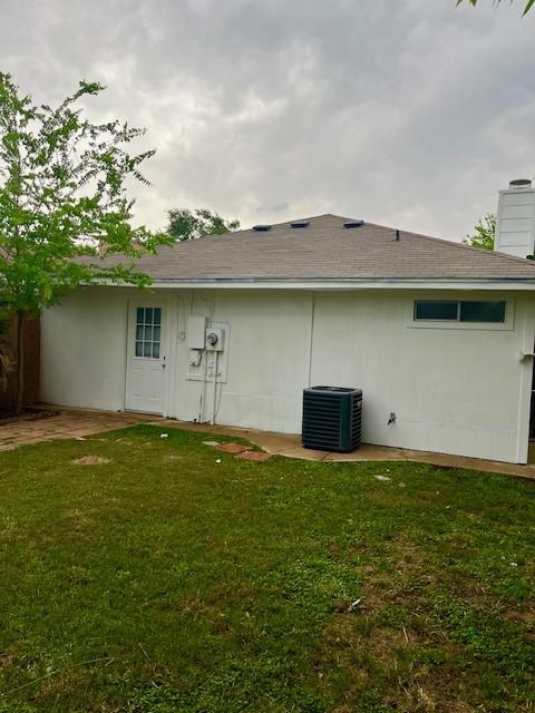 back of property featuring a lawn, central AC, and a chimney