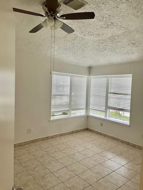 unfurnished room with light tile patterned floors, plenty of natural light, and a textured ceiling