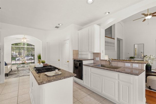 kitchen with a ceiling fan, black appliances, a sink, and arched walkways