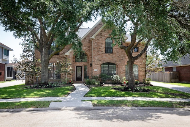 view of front of property with brick siding, fence, and a front yard