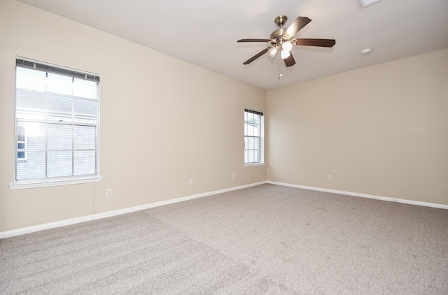carpeted spare room featuring baseboards and ceiling fan