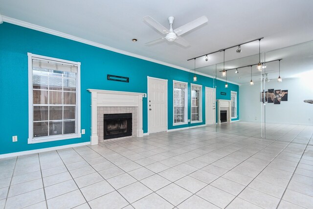 unfurnished living room with a fireplace, rail lighting, a ceiling fan, light tile patterned floors, and ornamental molding