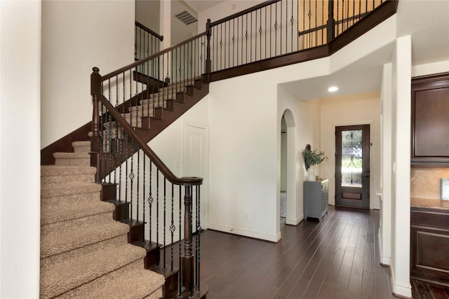 12542 Savage Ct, Magnolia, TX 77354 - stairway featuring arched walkways, wood finished floors, baseboards, and a towering ceiling