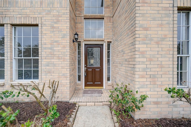 view of exterior entry featuring brick siding