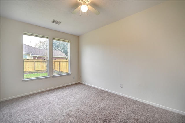 carpeted empty room with visible vents, a ceiling fan, and baseboards