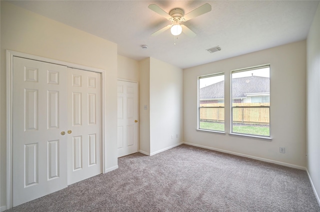 unfurnished bedroom with carpet flooring, baseboards, visible vents, and a closet