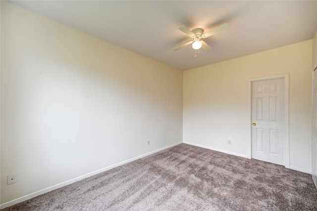 carpeted spare room featuring ceiling fan and baseboards