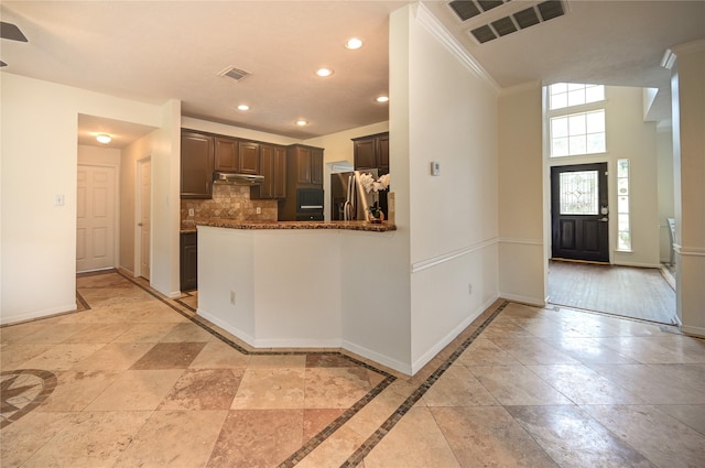 kitchen with baseboards, under cabinet range hood, a healthy amount of sunlight, and stainless steel fridge with ice dispenser