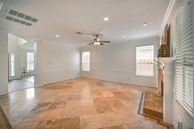 spare room with crown molding, baseboards, a ceiling fan, and visible vents