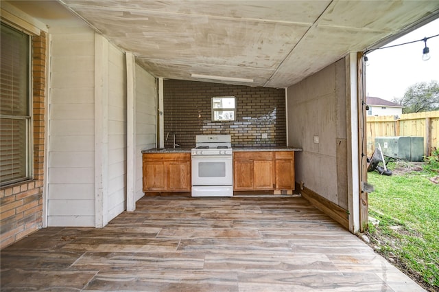 kitchen with a sink, wood finished floors, brown cabinets, and white gas range