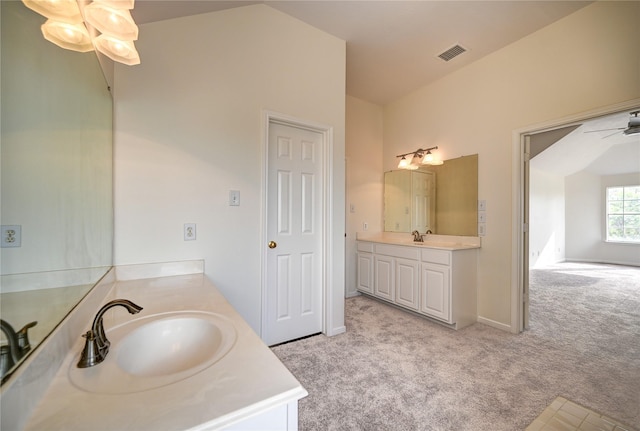 bathroom with a sink, a ceiling fan, two vanities, lofted ceiling, and visible vents