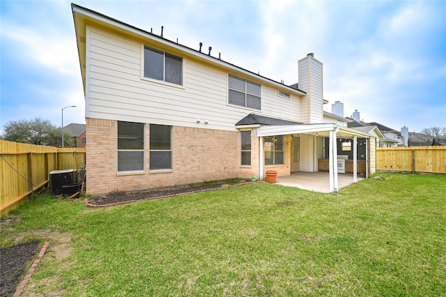 rear view of property with cooling unit, a fenced backyard, brick siding, a patio area, and a lawn