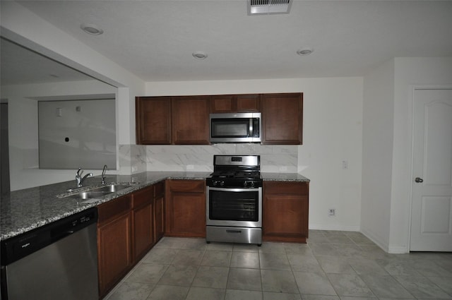 kitchen featuring stainless steel appliances, visible vents, a sink, and dark stone countertops