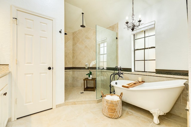 bathroom with tile walls, a soaking tub, walk in shower, and a notable chandelier