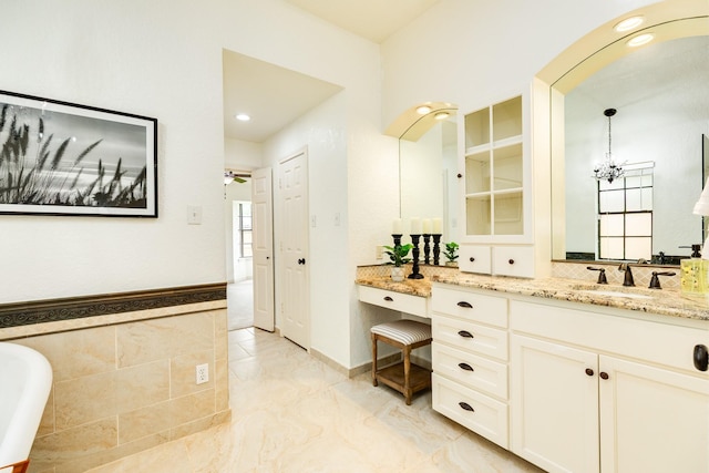 full bathroom with a chandelier, a freestanding bath, recessed lighting, and vanity