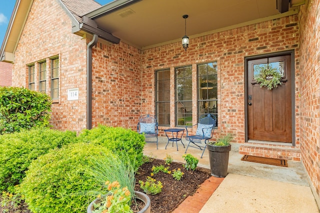 property entrance with a porch and brick siding