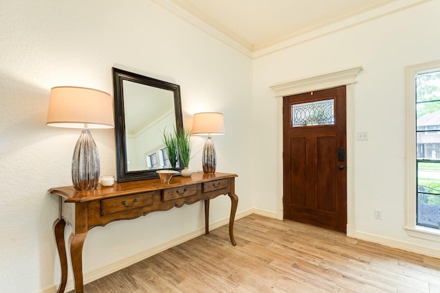 foyer entrance with crown molding, baseboards, and light wood-style flooring