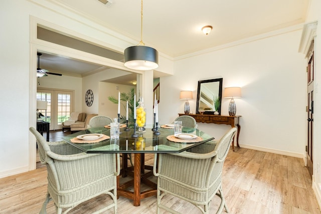 dining room with crown molding, a ceiling fan, light wood-style flooring, and baseboards