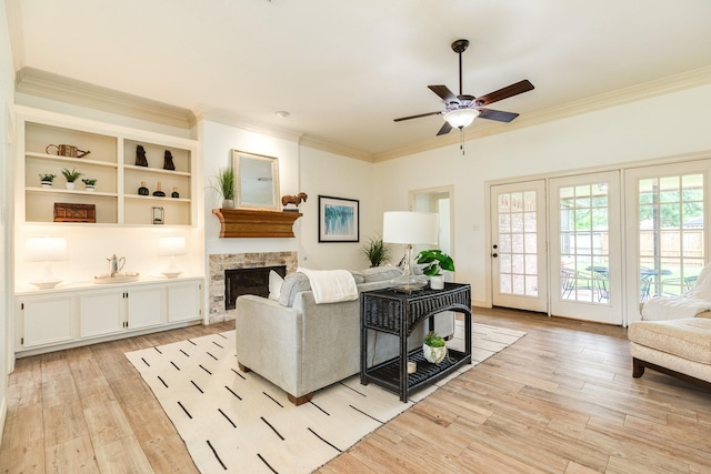 living room featuring crown molding, ceiling fan, light wood finished floors, and a fireplace