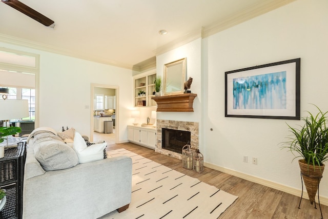 living room featuring baseboards, ornamental molding, and light wood finished floors