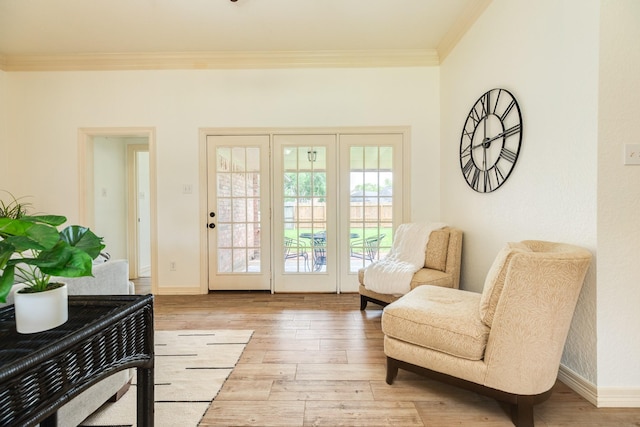 doorway to outside featuring baseboards, ornamental molding, and light wood-type flooring